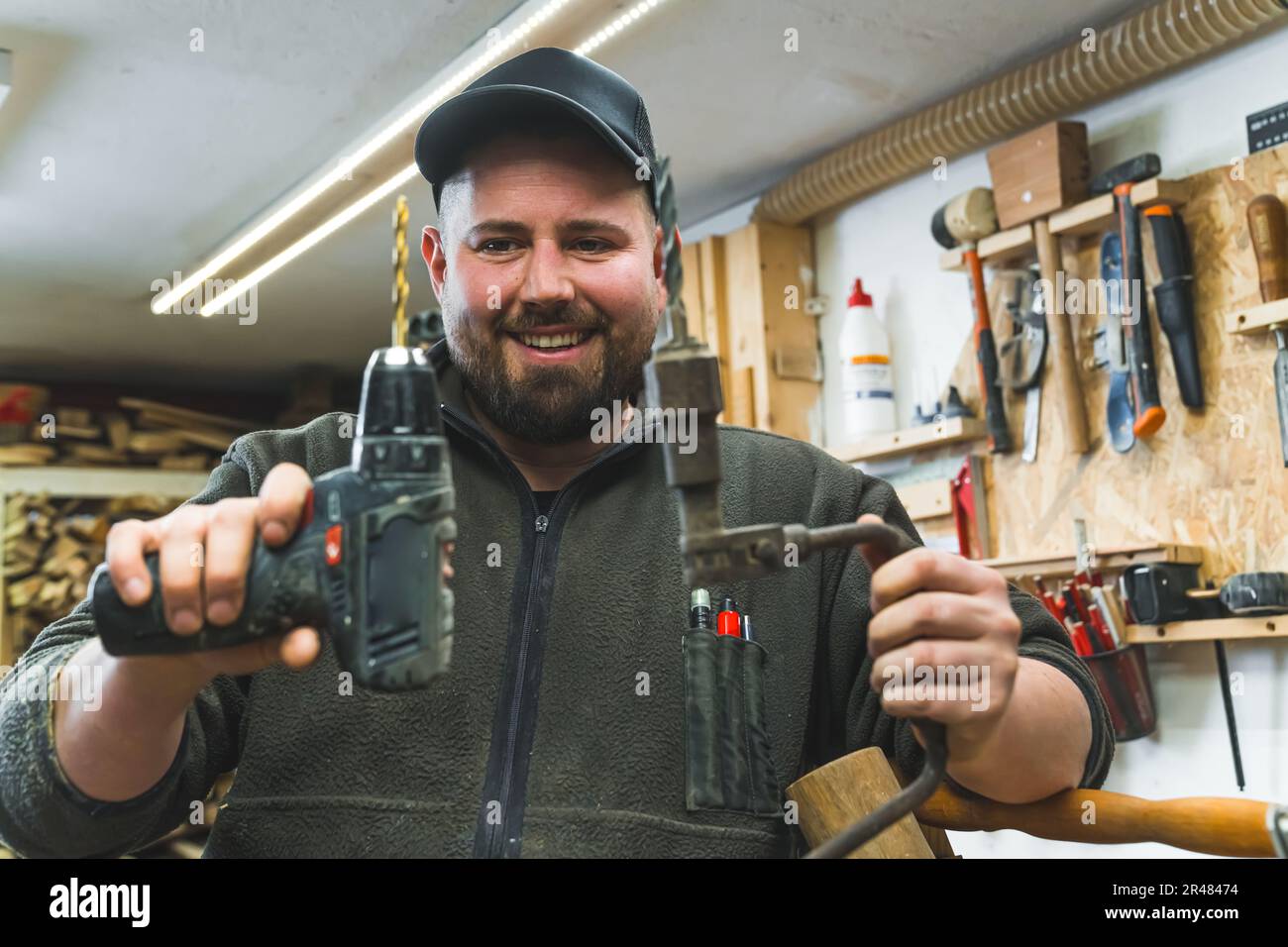 carpenter holding his drill and a brace in his repair shop, woodworking  concept. High quality photo Stock Photo - Alamy