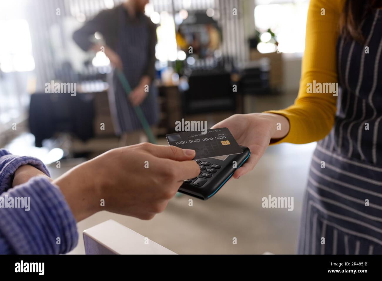 Hand of caucasian female client paying female hairdresser with credit