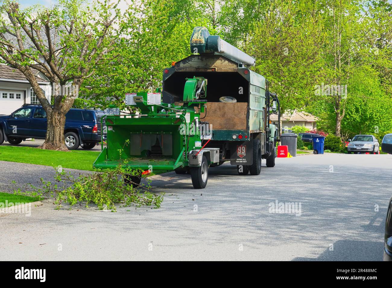 Tree chipping company truck with tree chipper on the job during springtime.  Maple Ridge, B. C., Canada. Stock Photo