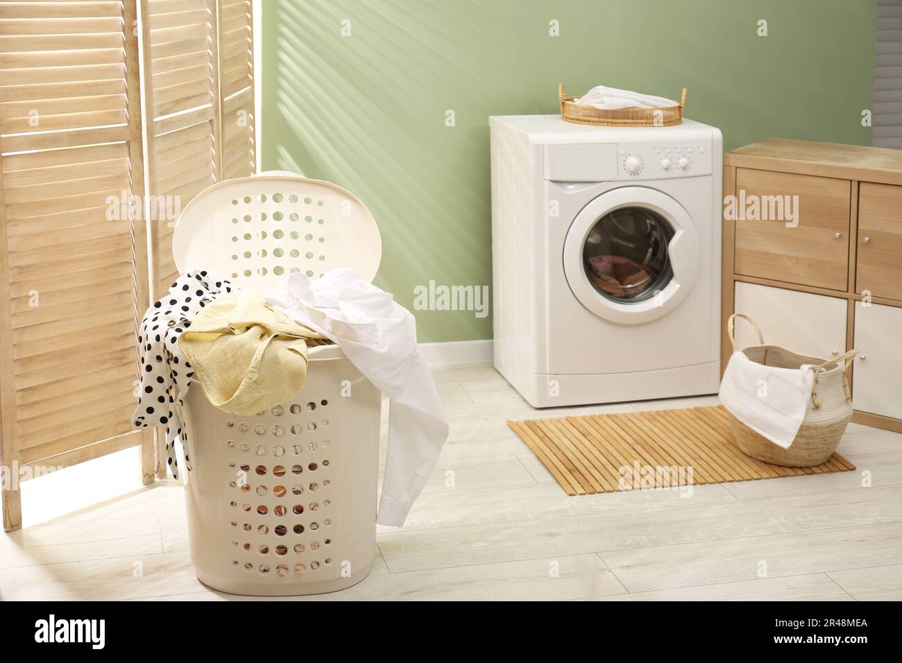 Laundry basket filled with clothes in bathroom. Space for text Stock
