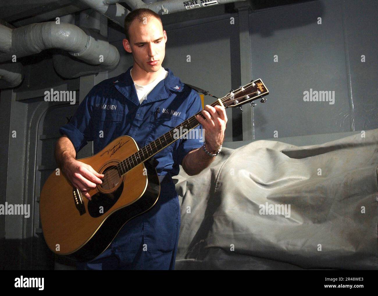 US Navy Sailor enjoys playing his guitar during some leisure time ...