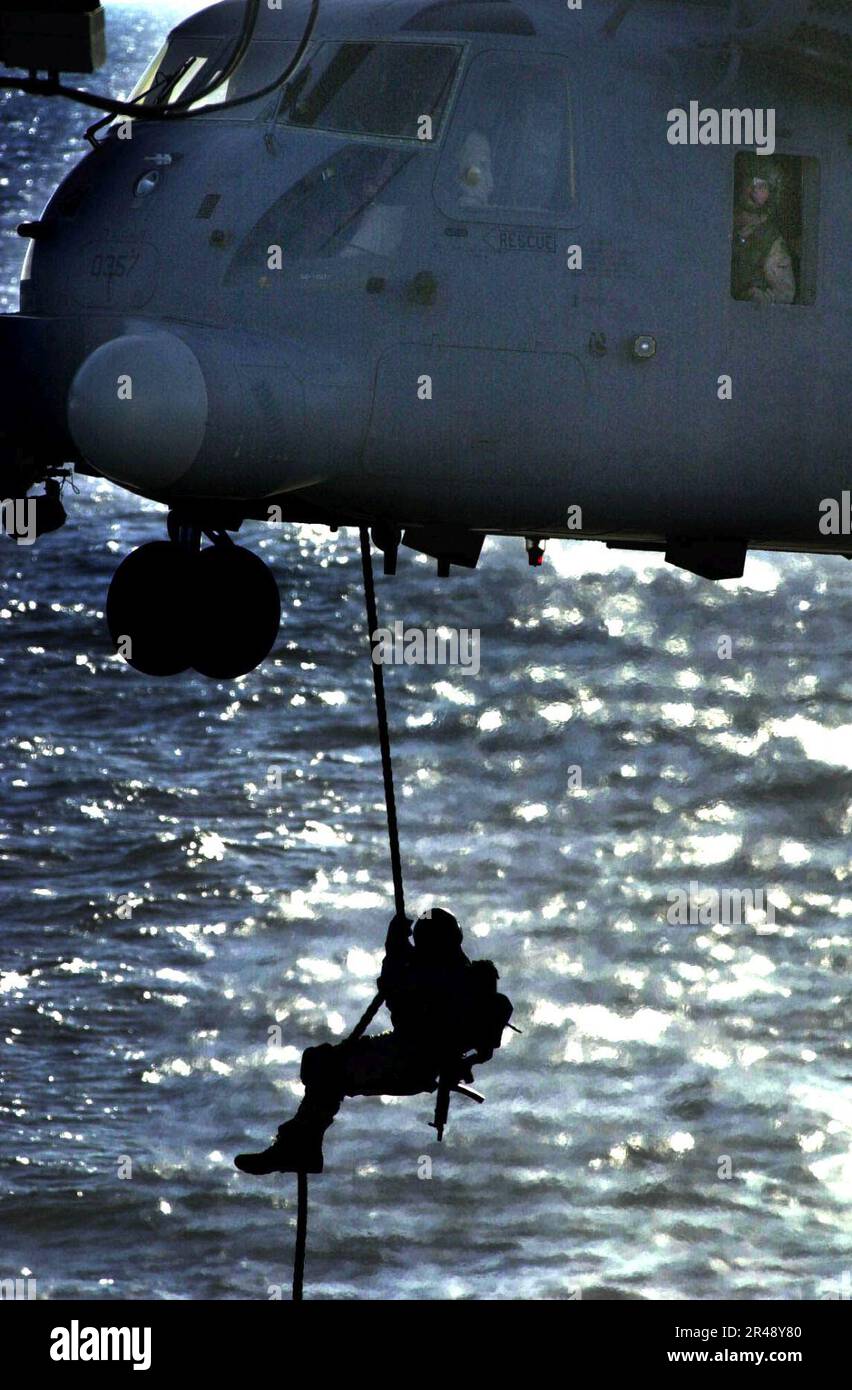 US Navy An unidentified U.S. Navy SEAL (SEa, Air, and Land) conducts a fast-rope insertion onto the deck of the amphibious command ship Stock Photo