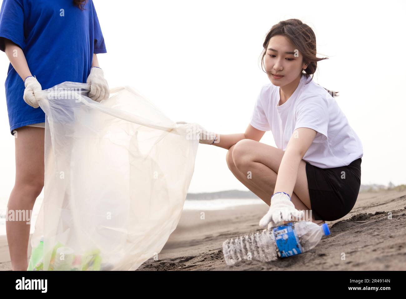 Young student collecting plastic waste on the beach. People cleaning the beach up Stock Photo