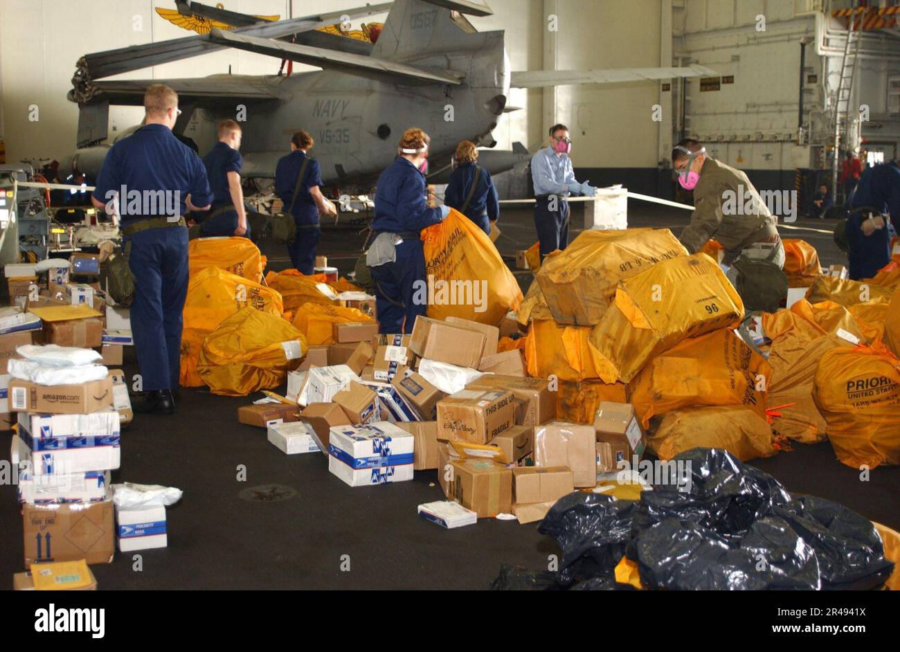 US Navy Crewmembers sort through the days mail staged in the hanger bay ...