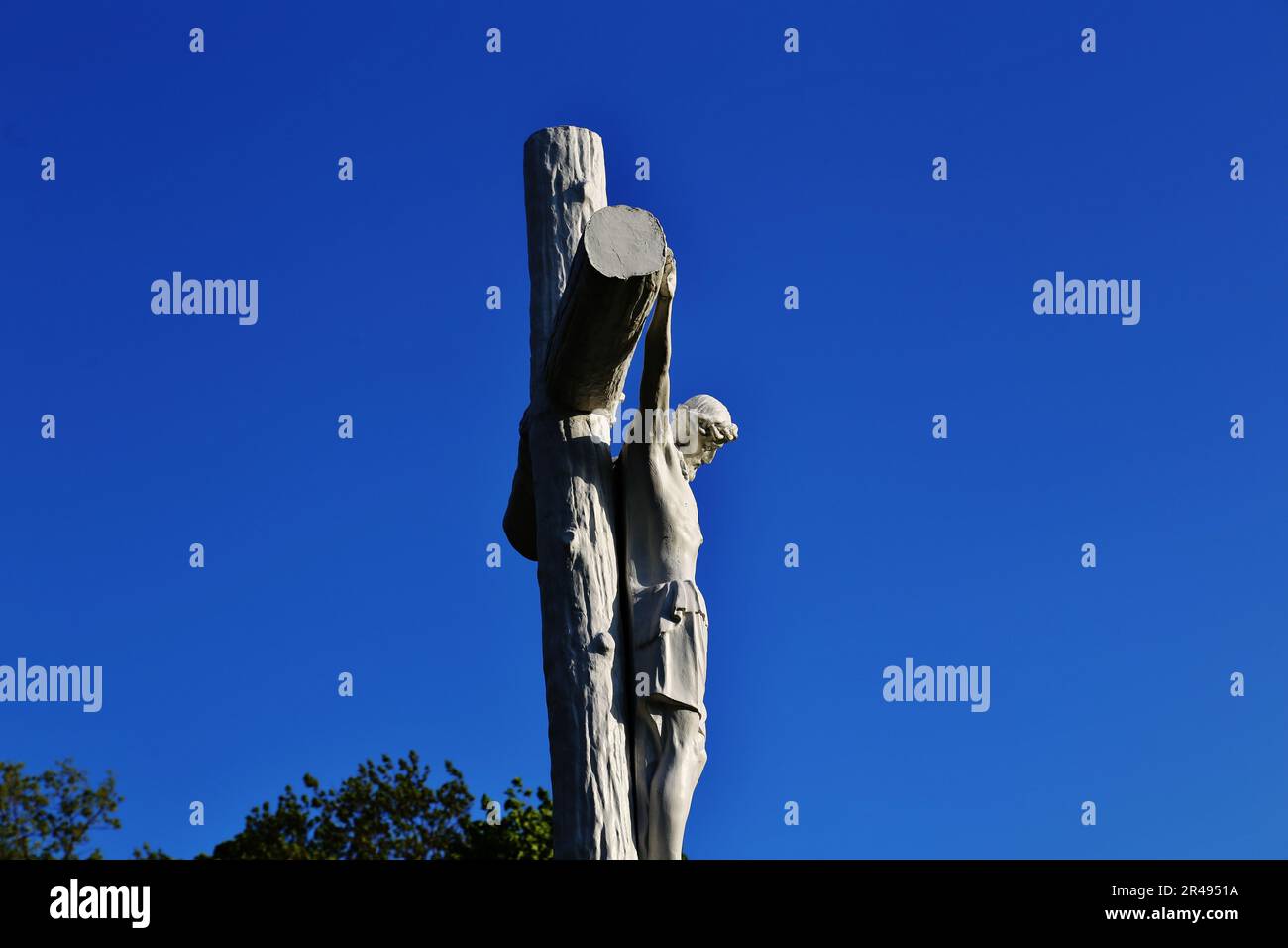 A statue of Jesus Christ on the cross against a bright blue sky Stock ...