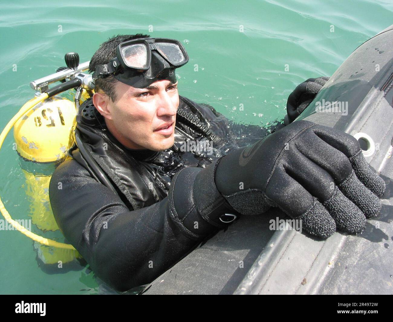 US Navy Construction Electrician Robert Soto surfaces to provide placement information to a range safety officer (RSO) after placing 65lbs of high explosives underwater during a recent joint debris clearing Stock Photo