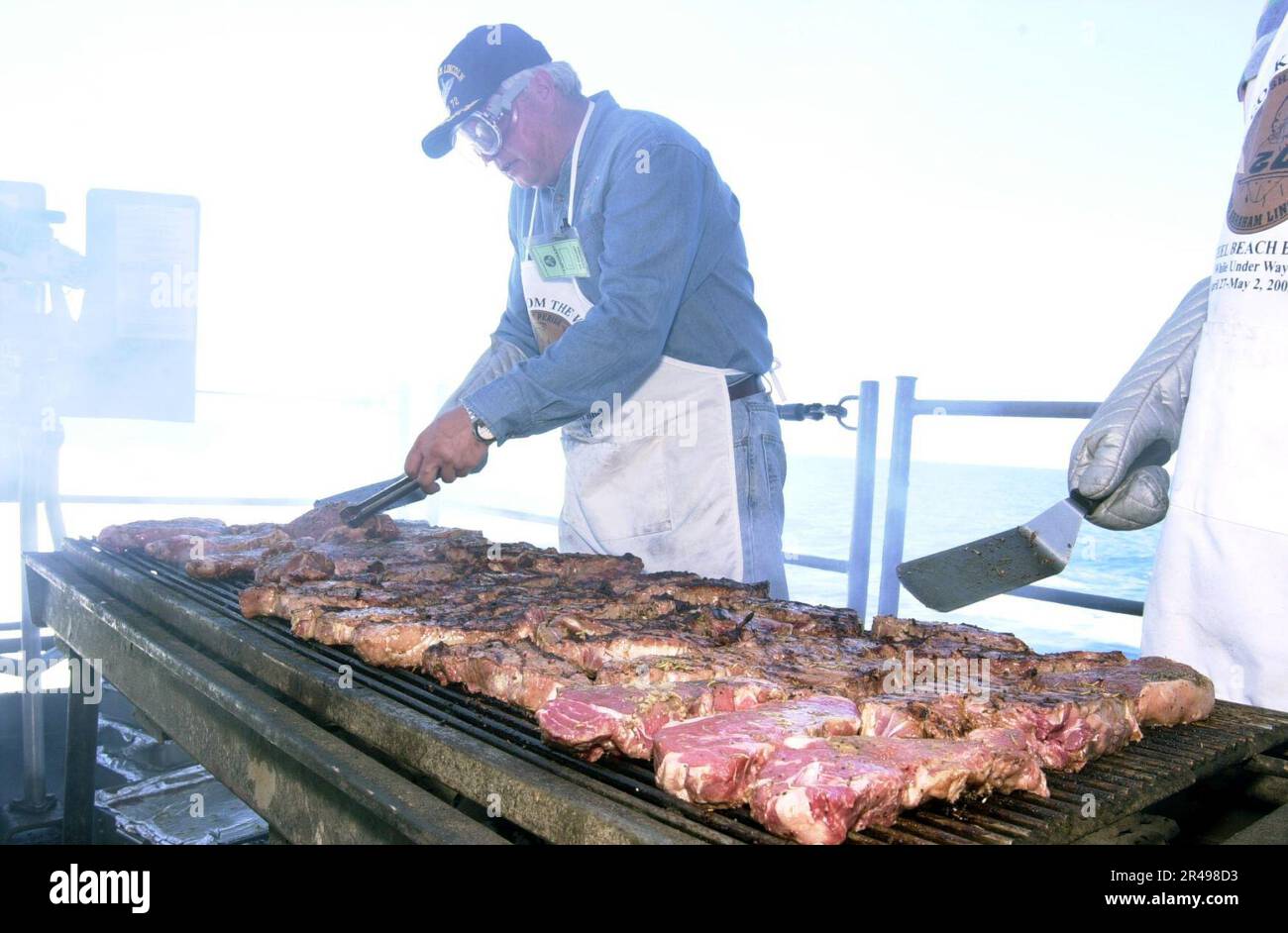 US Navy Volunteers from Harris Ranch Steakhouse barbecue steaks on the fantail for the crew to show their support for the USS Abraham Lincoln's (CVN 72) participation in Operation Iraqi Freedom Stock Photo