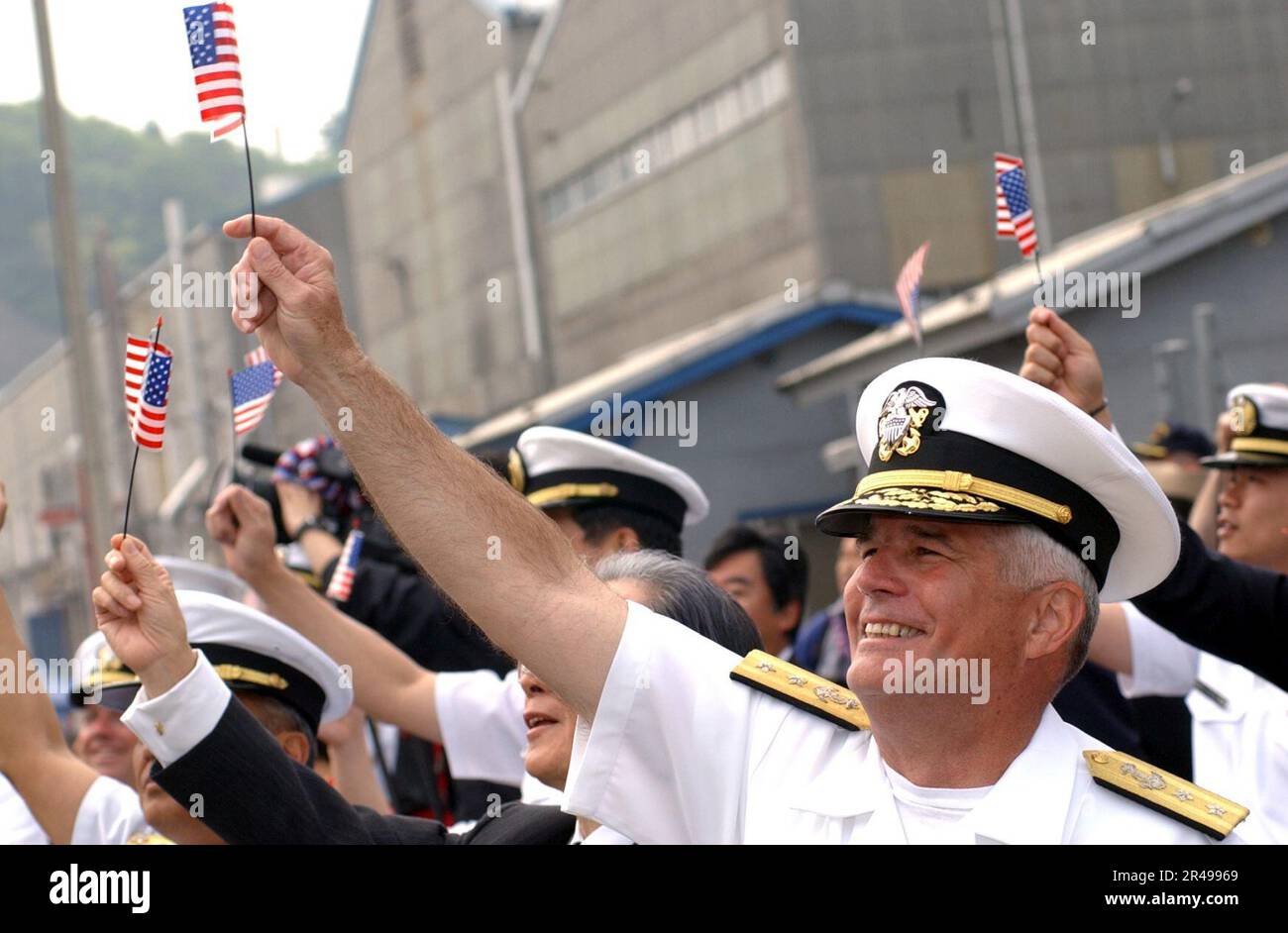 US Navy Rear Adm. Robert C. Chaplin, Commander, U.S. Naval Forces Japan waives an American flag as the USS Kitty Hawk (CV 63) returns home from conducting operations in support of Operation Iraqi Freedom Stock Photo