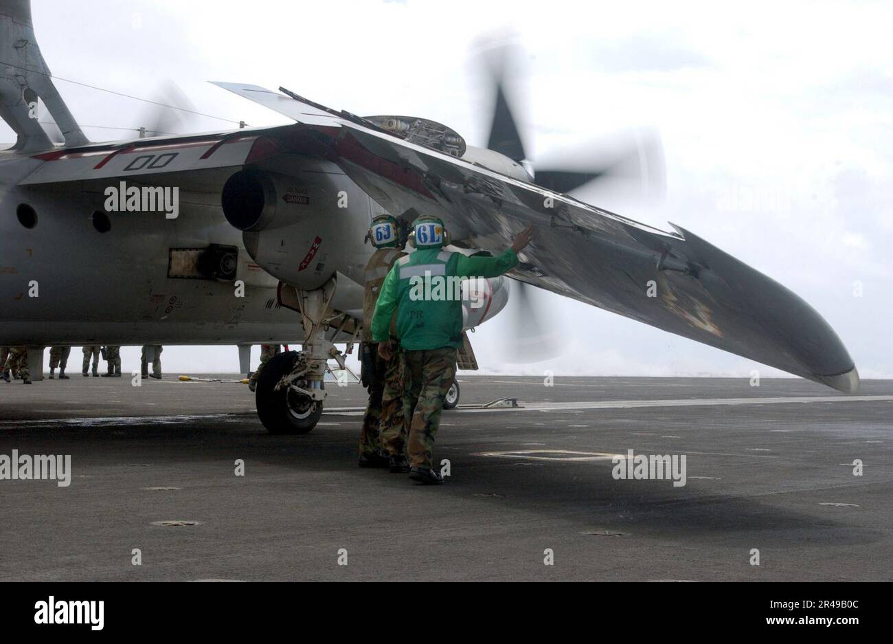 US Navy roubleshooters assigned to Airborne Early Warning Squadron One Twelve (VAW-112) walk the length of the wing of an E-2C Hawkeye as the wing unfolds on the flight deck aboard USS Carl Vinson (CVN 70) Stock Photo