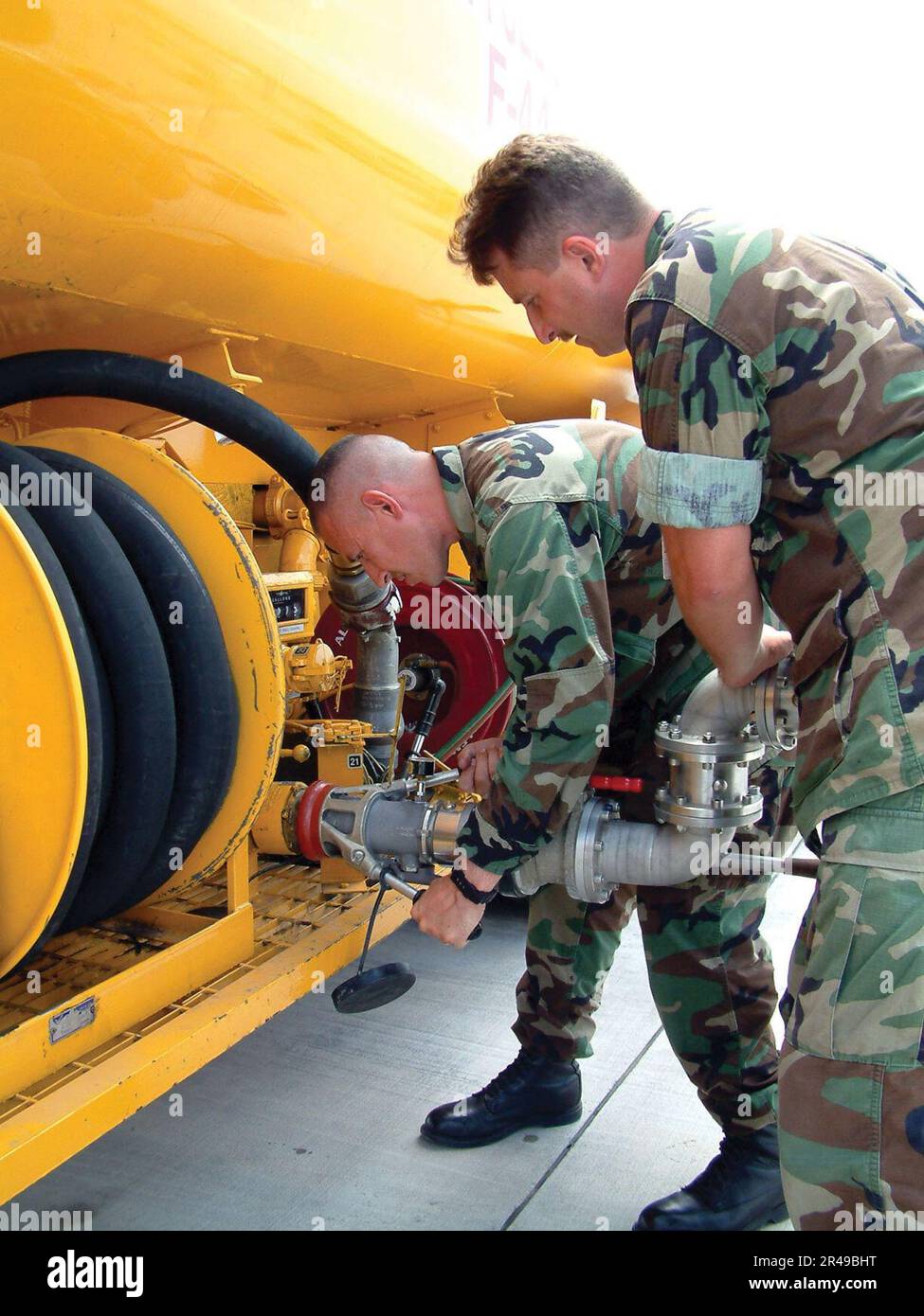 US Navy Lt. Cmdr. and Aviation Boatswains' Mate 1st Class connects a ...