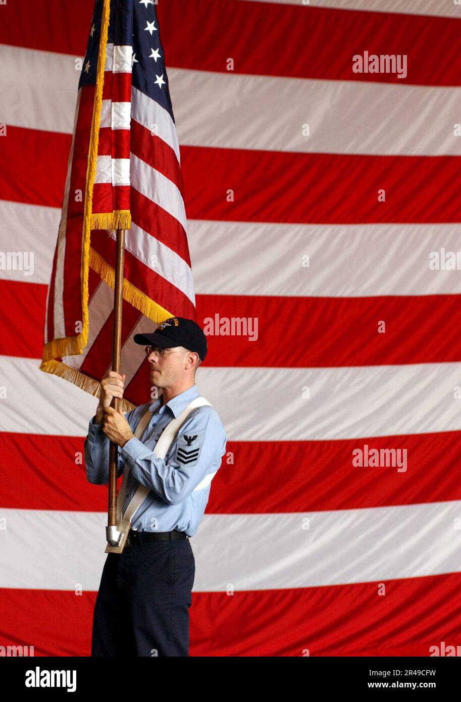 US Navy Personnelman 1st Class carries the National Ensign during color guard rehearsals in