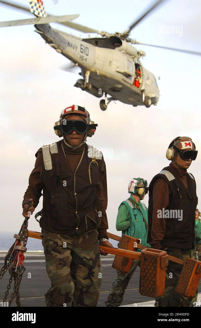 US Navy Flight deck crewmen clear the deck of chalks and tie-down ...