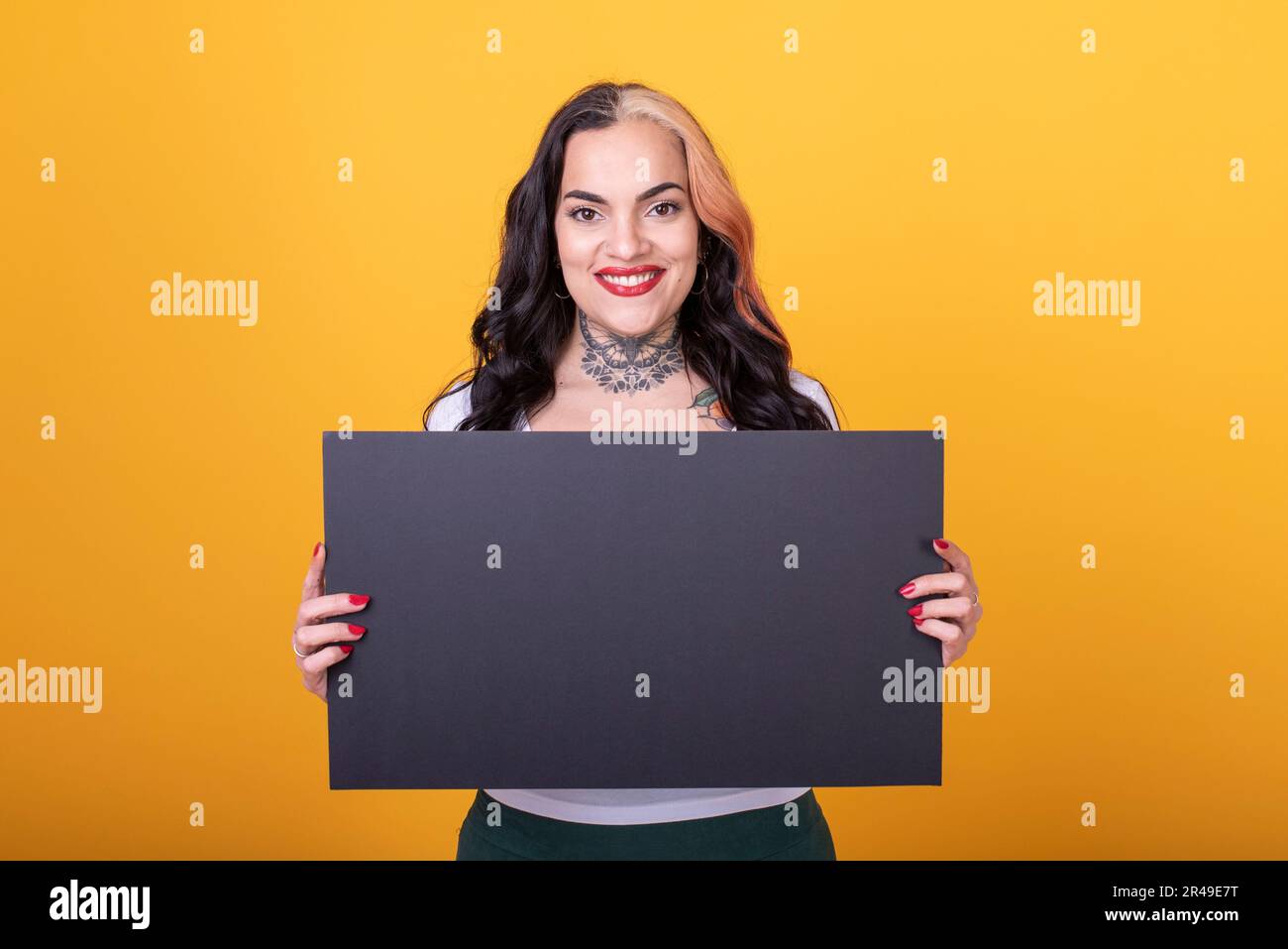 Beautiful woman holding a blank sign against a yellow background Stock Photo