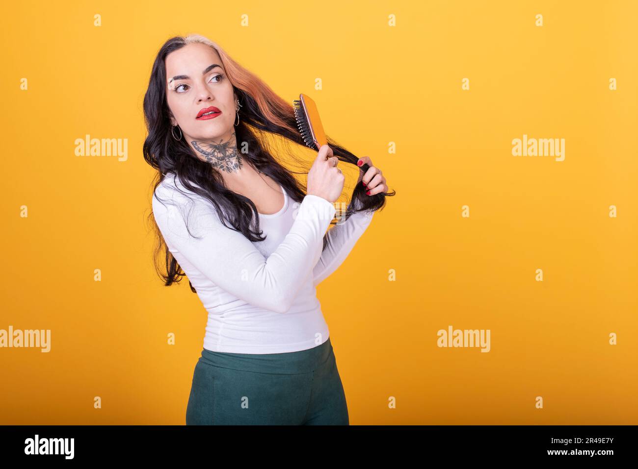Attractive Woman combing her hair over yellow background. Studio shot Stock Photo