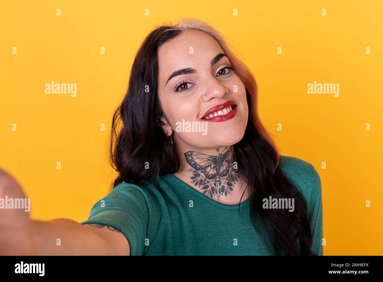 Portrait of an attractive woman making a selfie over yellow background. Studio shot. Stock Photo