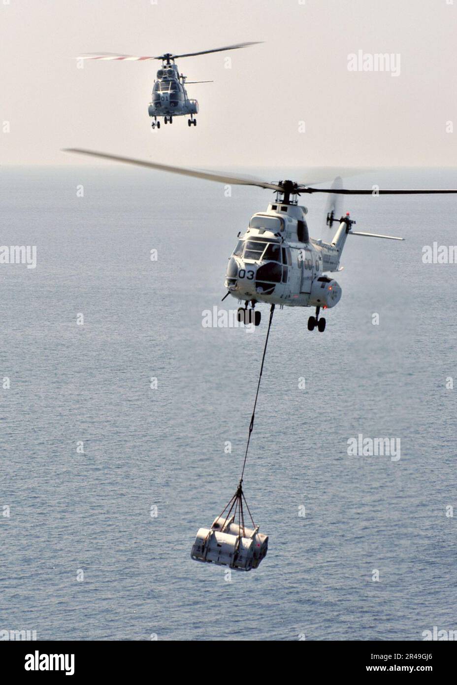 US Navy An SA-330 Puma helicopter carries supplies from Military Sealift Command ship, USNS Saturn (TAFS 10) over to the aircraft carrier USS Enterprise (CVN 65) during a Replenishment at Sea (RAS) Stock Photo