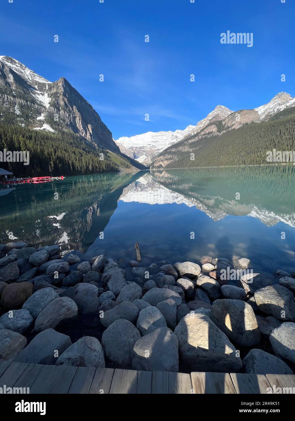 A vertical shot of a serene lake mirroring the majestic mountains in ...