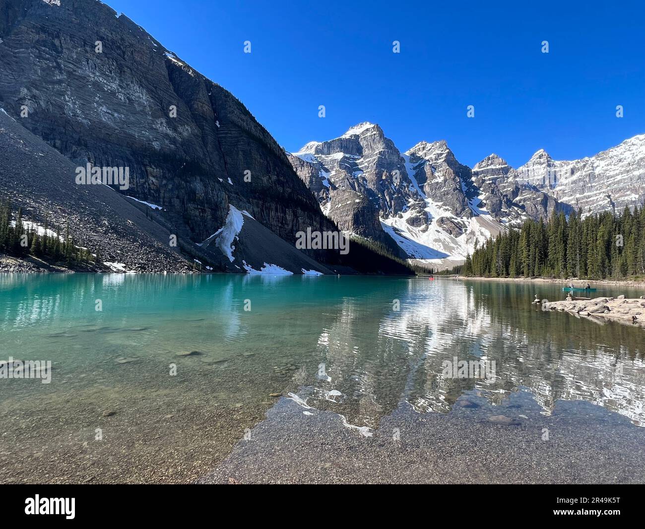 A scenic view of a lake situated in a mountainous landscape, with crystal blue waters lapping against the shoreline Stock Photo
