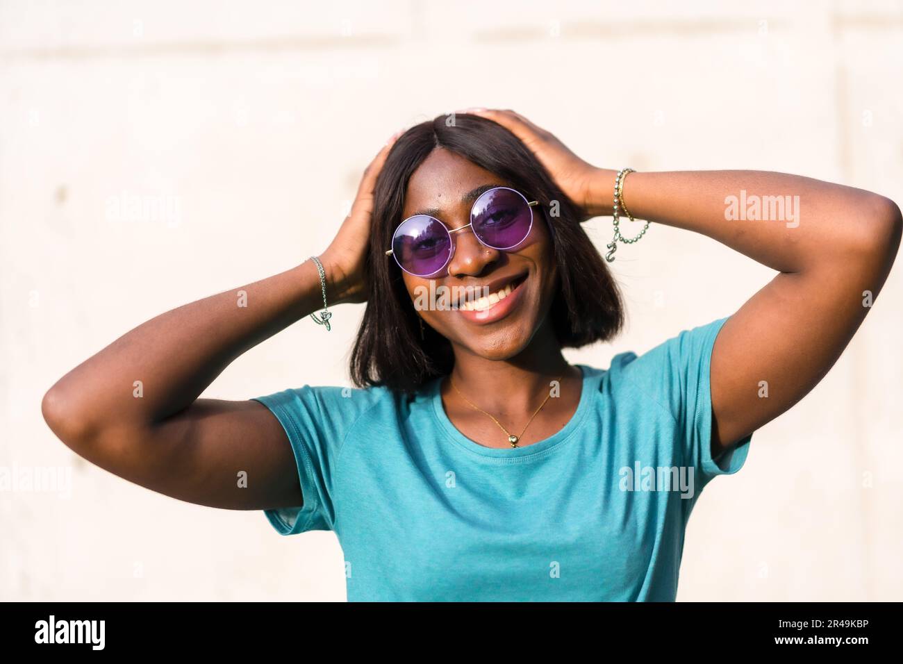 A stylish young black female in sunglasses standing against a wall in ...