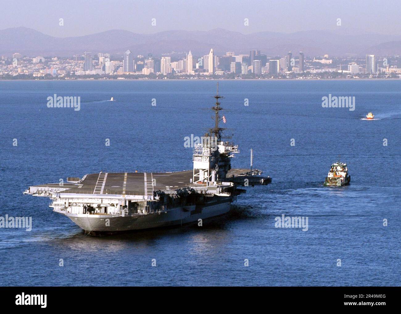 US Navy A tugboat tows the aircraft carrier Midway into San Diego bay Stock Photo