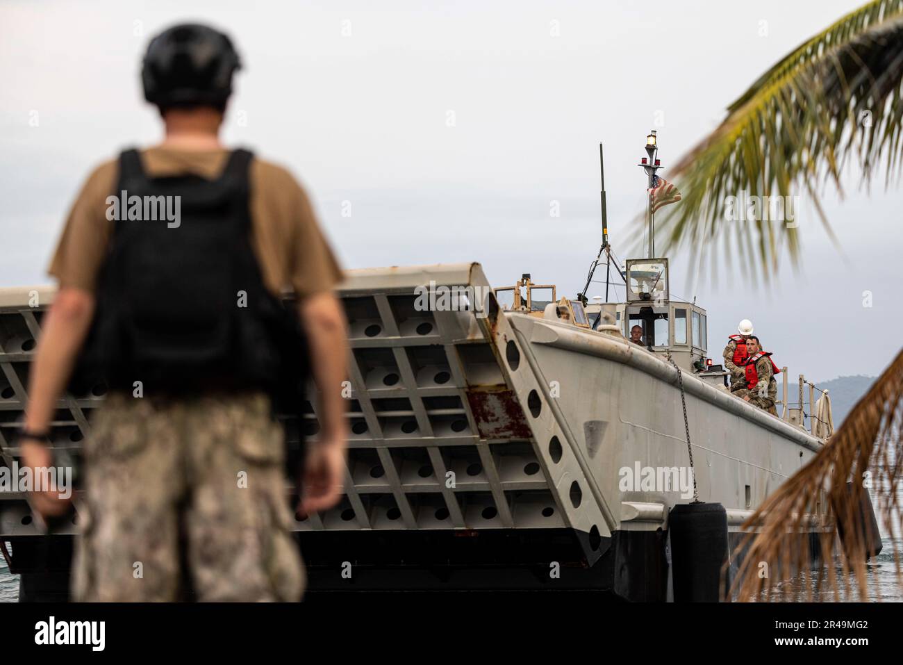A U.S. Navy Sailor watches as an Army Landing Craft Mechanized drops its ramp during an offload in preparation for Balikatan 23 at Camp Agnew, Casiguran, Philippines, April 8, 2023. Balikatan is an annual exercise between the Armed Forces of the Philippines and U.S. military designed to strengthen bilateral interoperability, capabilities, trust, and cooperation built over decades shared experiences. Stock Photo