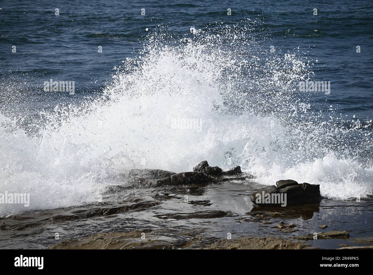 A beautiful shot of foamy waves splashing against a rocky seashore ...