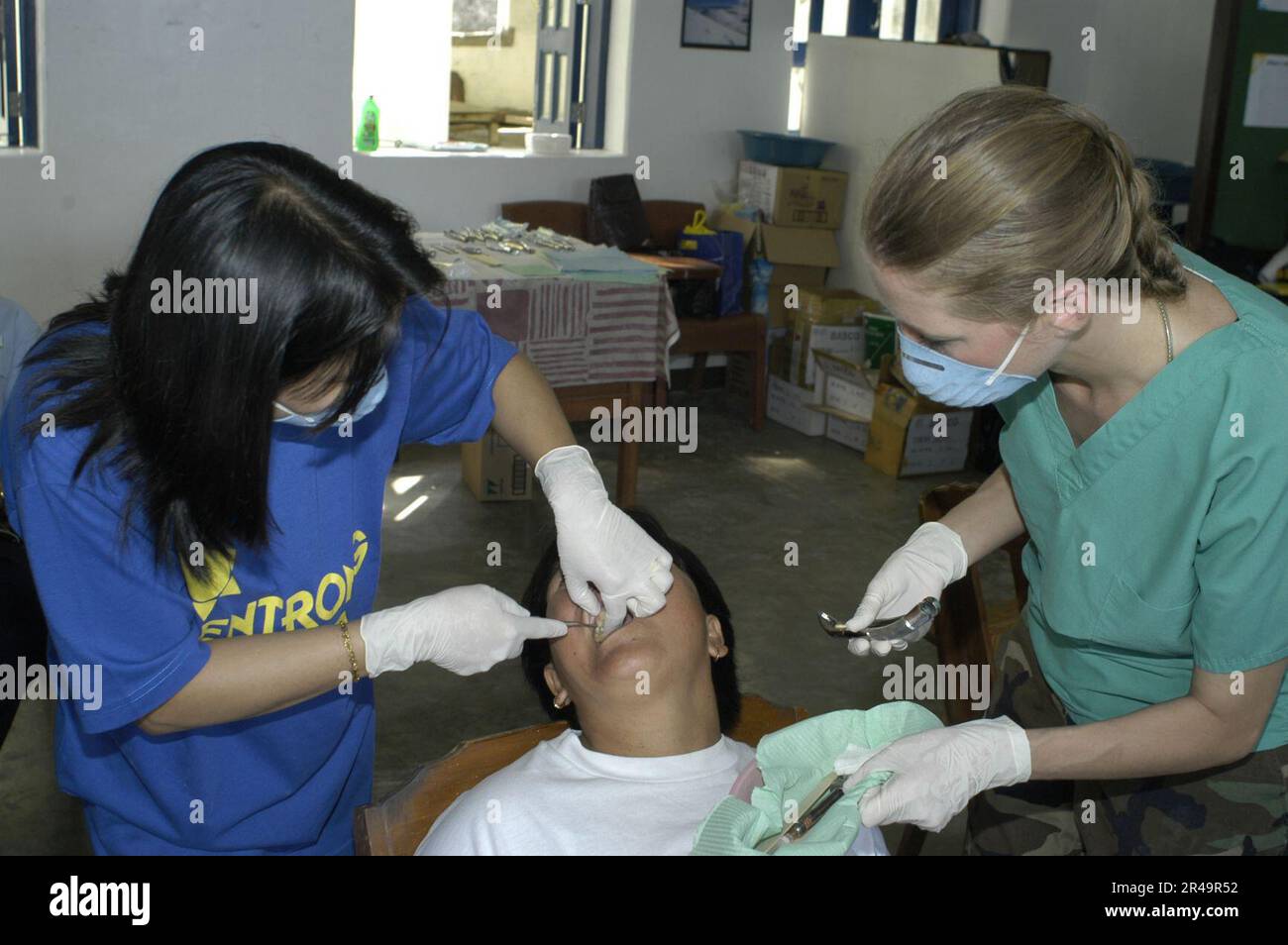 US Navy Filipino dentist left, and Naval Reserve Dental Technician 1st Class treat local