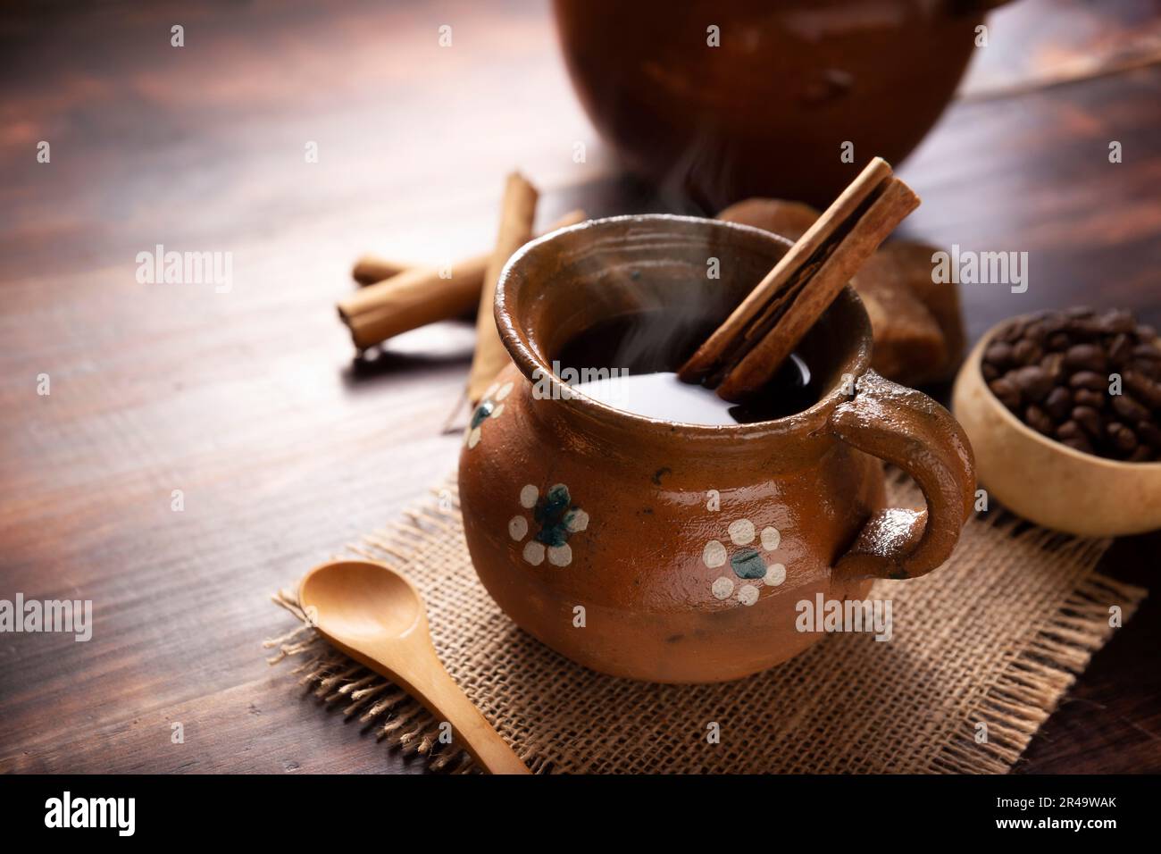 Authentic homemade mexican coffee (cafe de olla) served in traditional handmade clay mug (Jarrito de barro) on rustic wooden table. Stock Photo