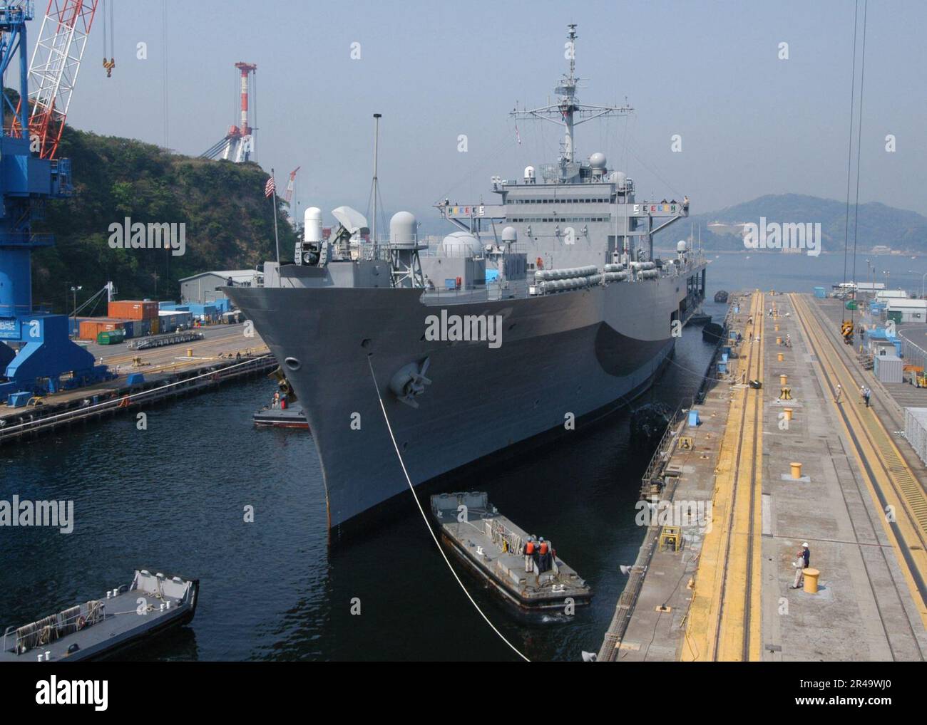 US Navy Small barges maneuver the 7th Fleet command and control ship ...