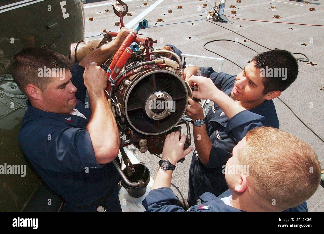 US Navy Sailors work together to repair a damaged engine on an SH-3 Sea King helicopter aboard USS Coronado (AGF 11) Stock Photo