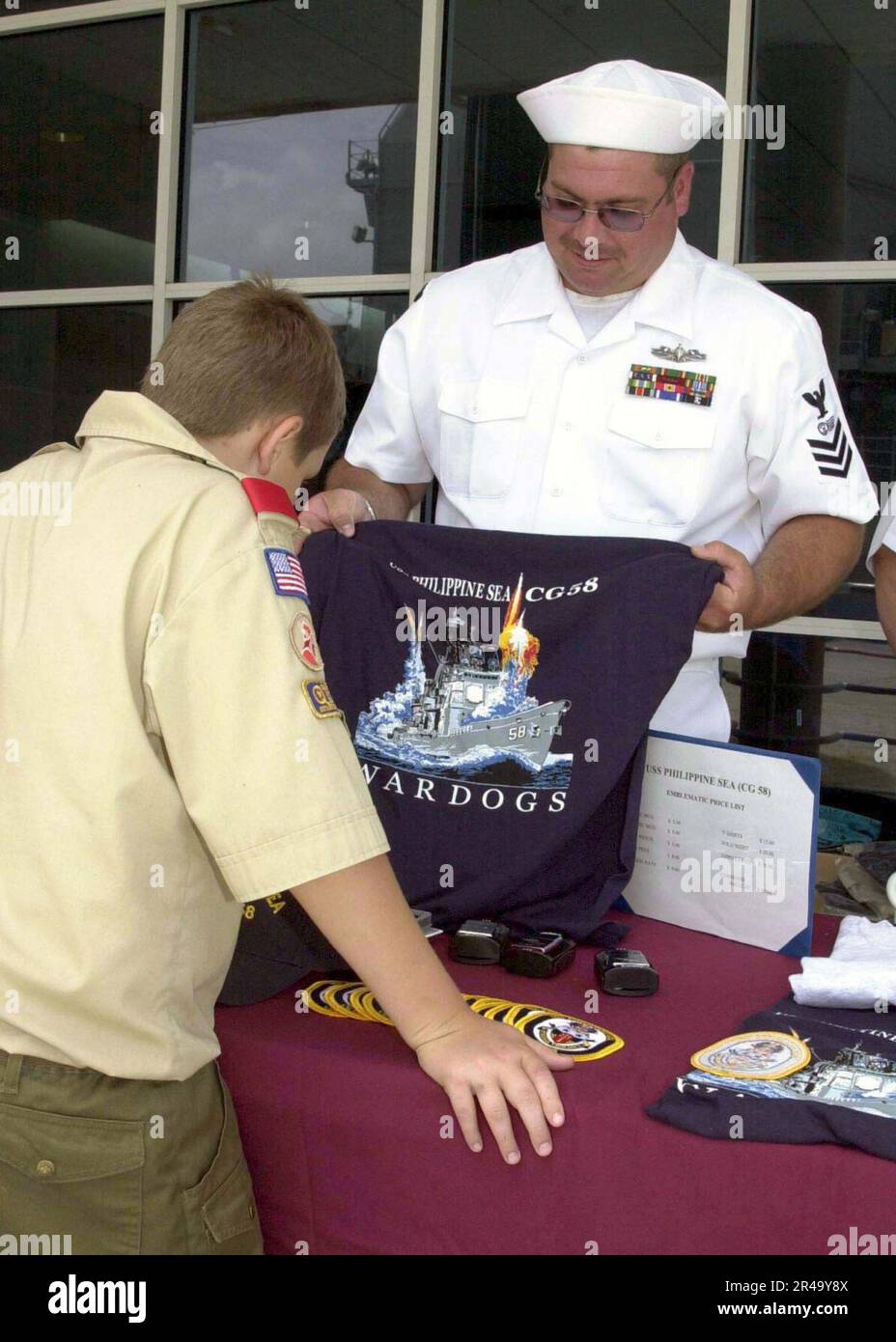 US Navy Postal Clerk 1st Class sells command ball caps and shirts to