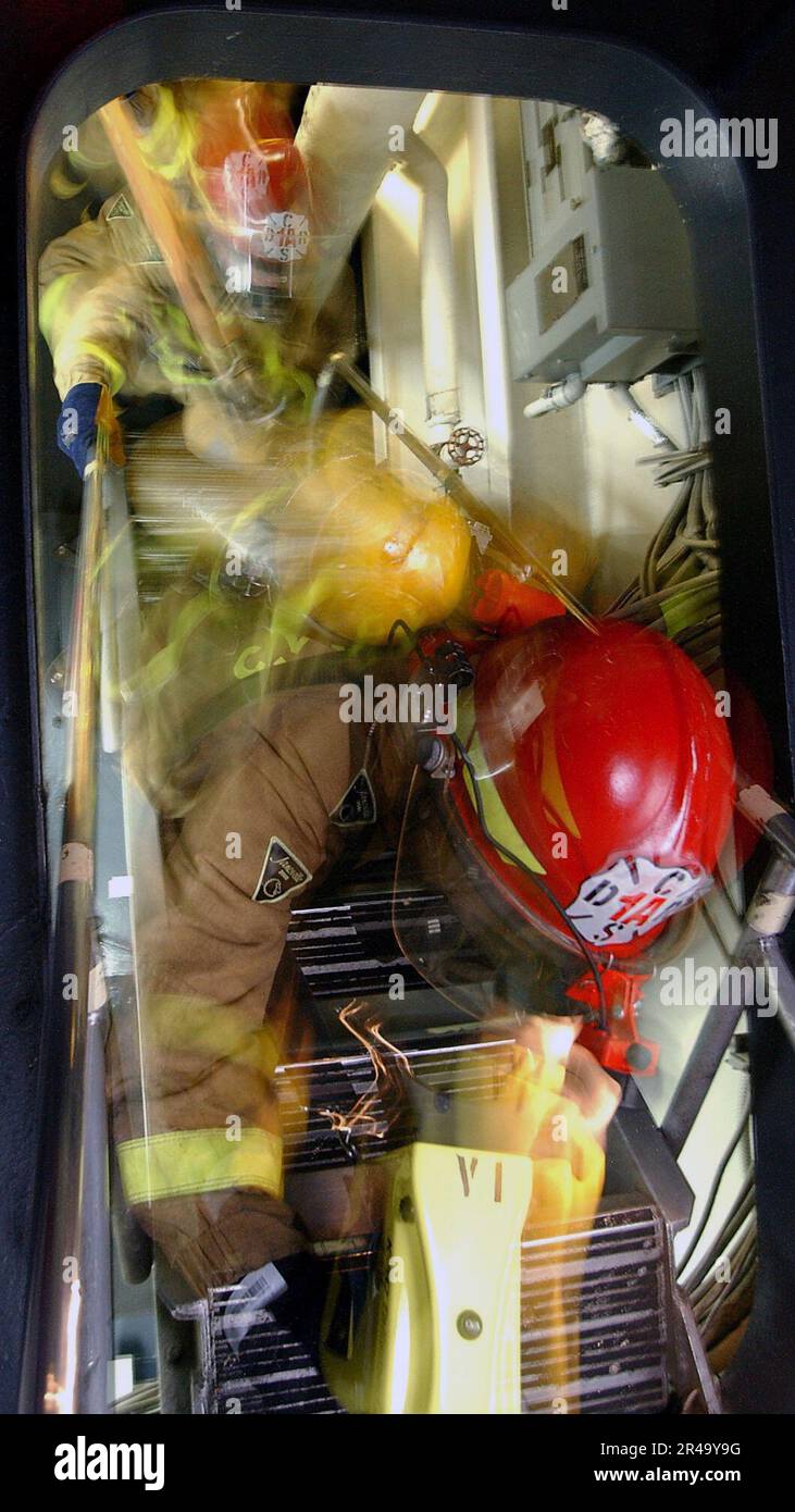 US Navy Fire team members assigned to the ship's damage control Repair Locker 1A, climb a ladder while responding to a simulated fire during a General Quarters (GQ) drill aboard USS George Washington (CVN 73) Stock Photo