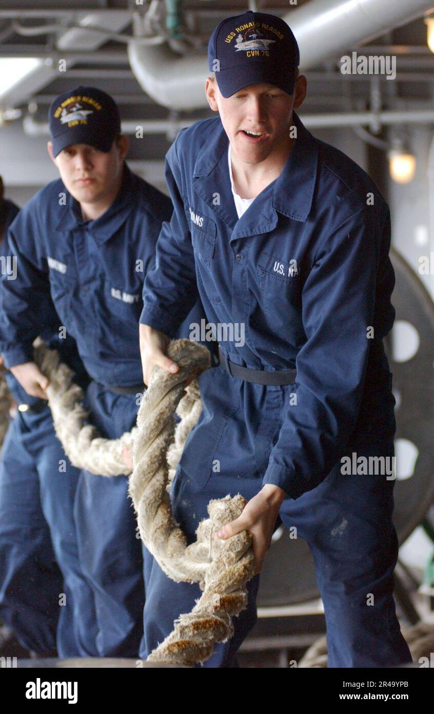 US Navy Deck Department crew members single up a mooring line as USS ...