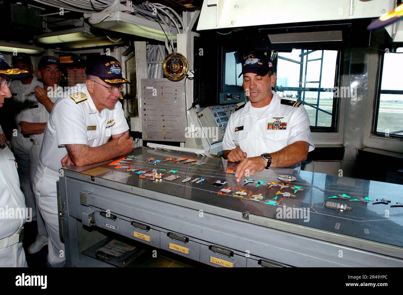 US Navy  Adm. Vern Clark, Chief of Naval Operations (CNO), looks on as Lt.j.g. demonstrates flight deck operating procedures in Flight Deck Control. Stock Photo