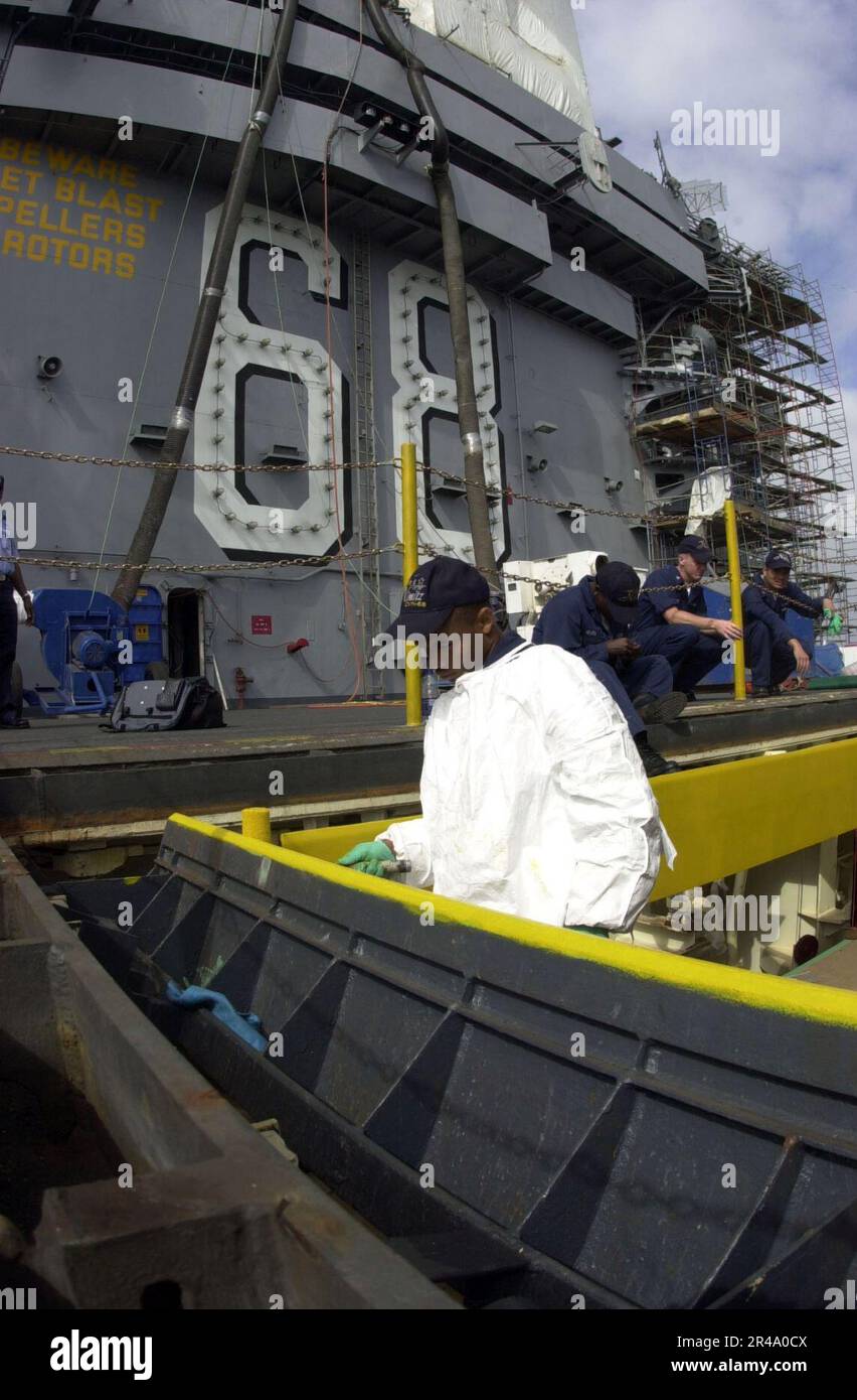 US Navy Aviation Ordnanceman Airman paints boundary markings around an ...