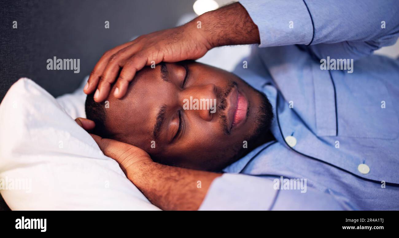 Young African Man Suffering From Fever Lying On Bed Stock Photo