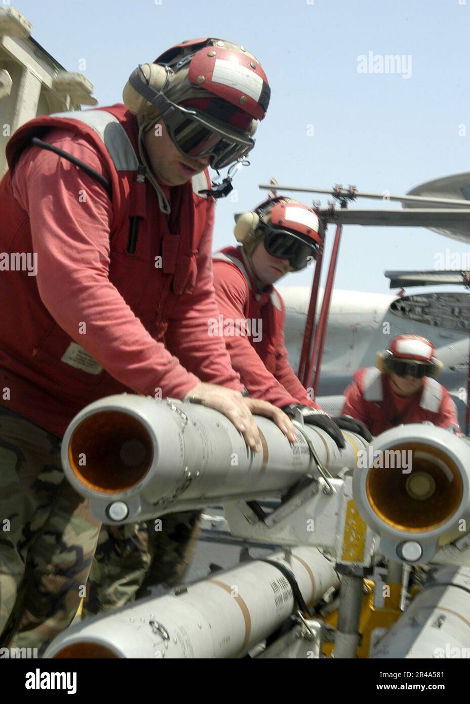 US Navy Crew members move a skid of AIM-9L Sidewinder missiles across ...