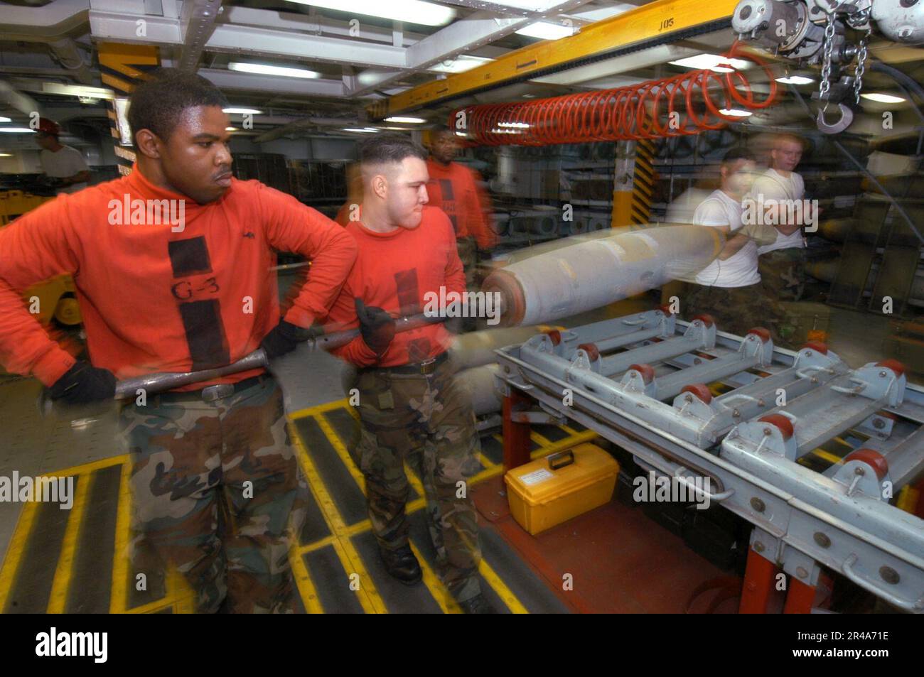 US Navy Members of G-3 bomb assembly division move a MK-82 500lb general-purpose bomb base to an assembly line aboard USS John F. Kennedy (CV 67) Stock Photo