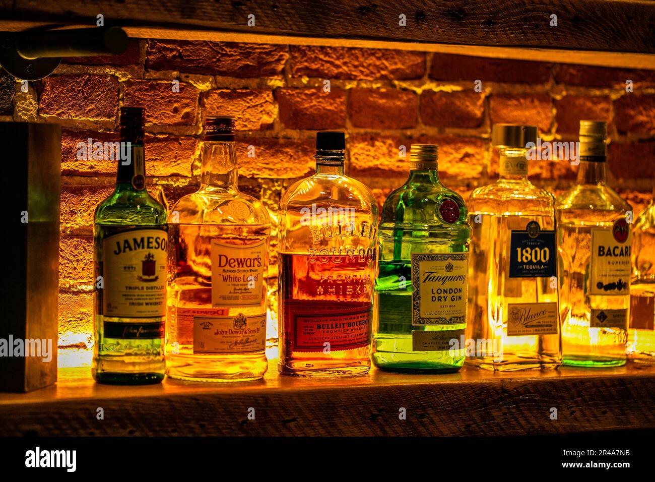 A closeup of a shelf of various types of alcoholic beverage bottles