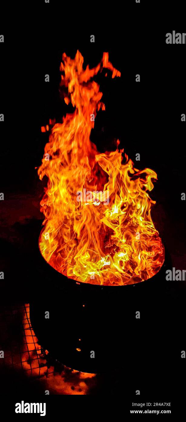 A black bowl sits illuminated by a bright orange flame in a dark setting Stock Photo