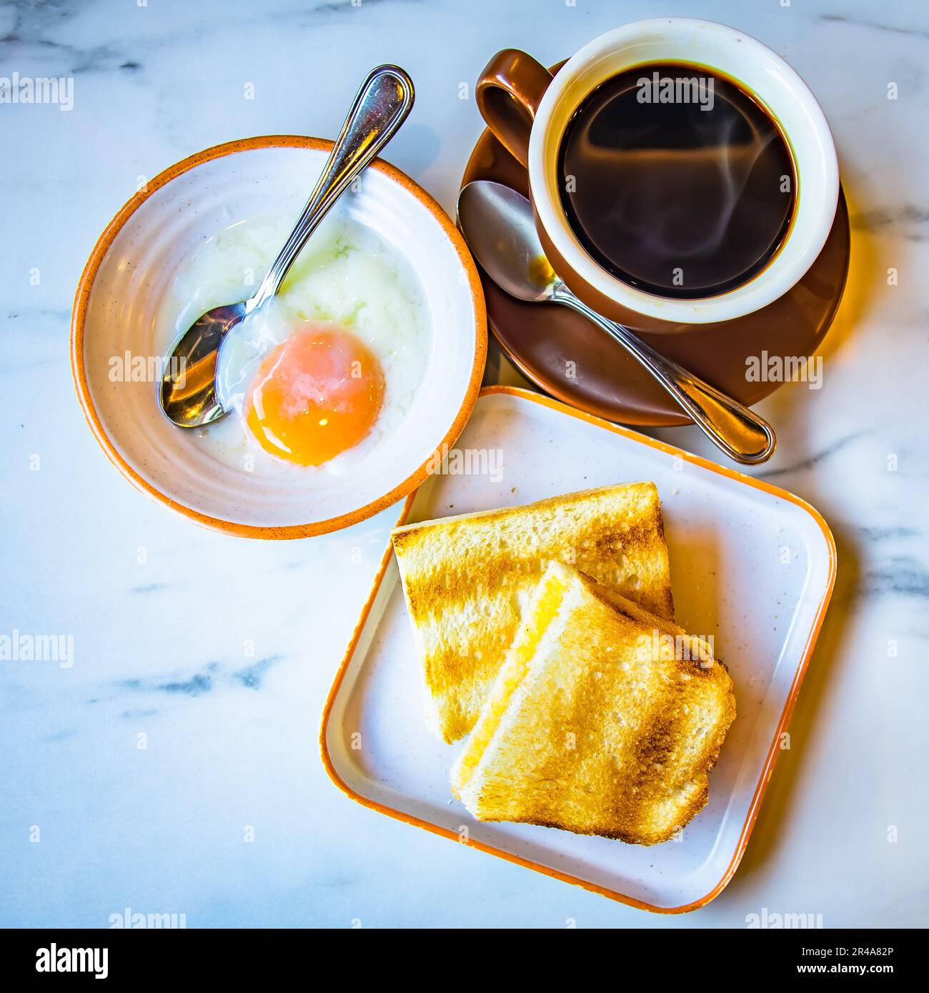 Traditional coffee shop breakfast meals. Black Coffee, Half-Boiled Eggs and Toast. Authentic Hainanese way of food. Stock Photo