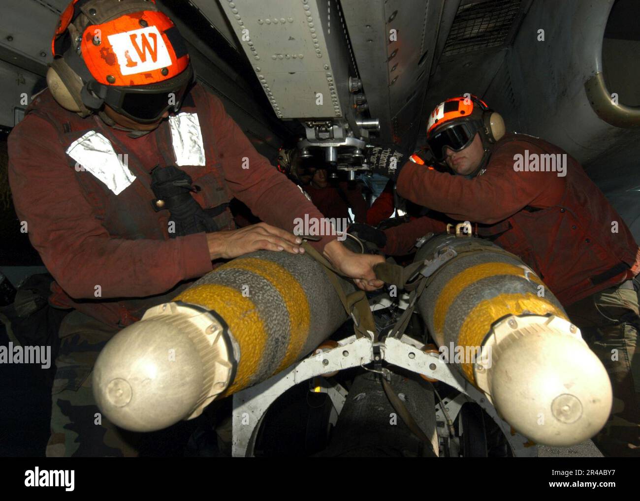 US Navy Aviation Ordnancemen make preparations to upload a Mk-83 1,000 pound general purpose bomb fitted with a proximity-fuze on an F-14B Tomcat Stock Photo