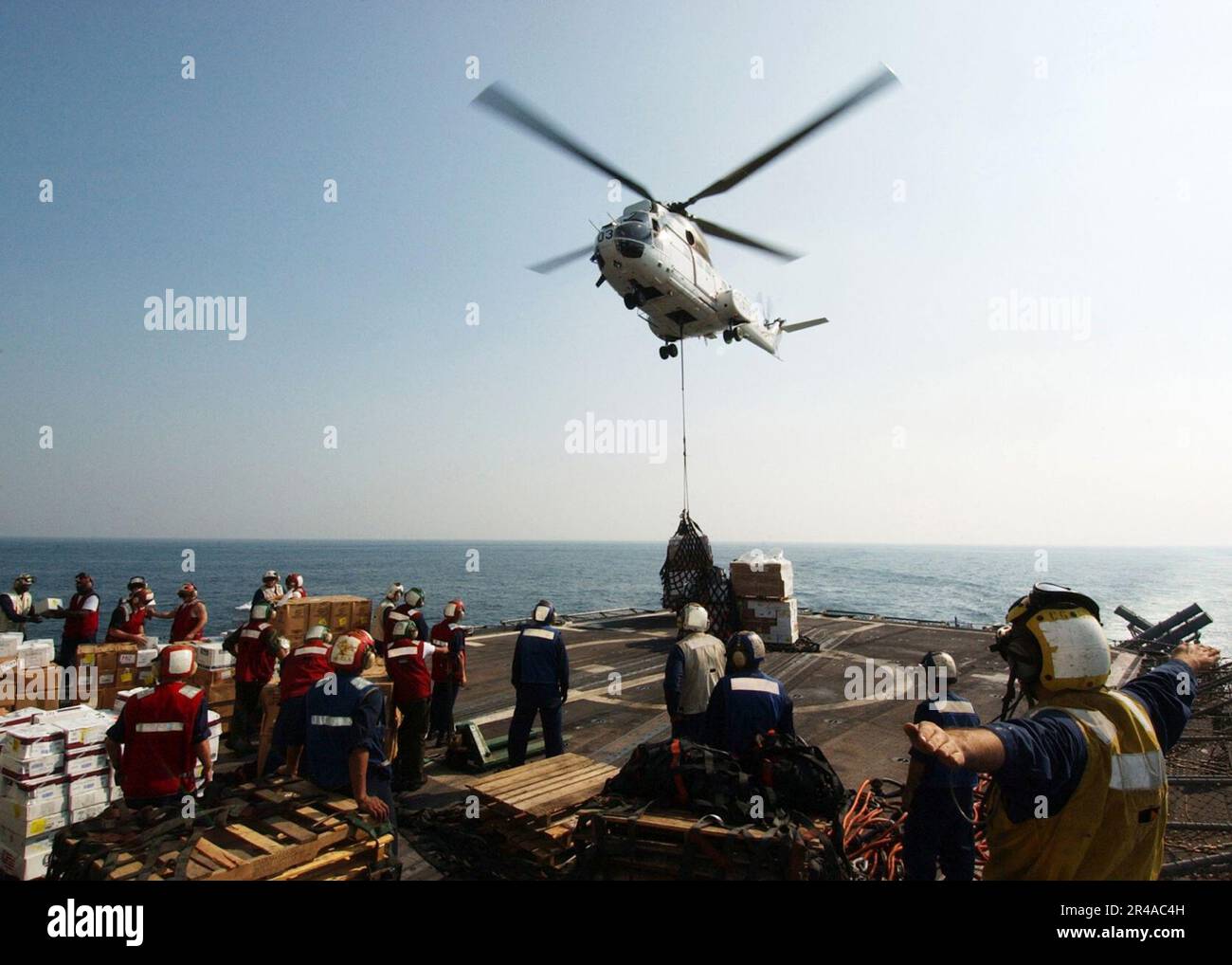 US Navy Sailors assigned to the guided missile cruiser USS Vicksburg (CG 69) receive pallets of stores from an SA-330 Puma helicopter Stock Photo