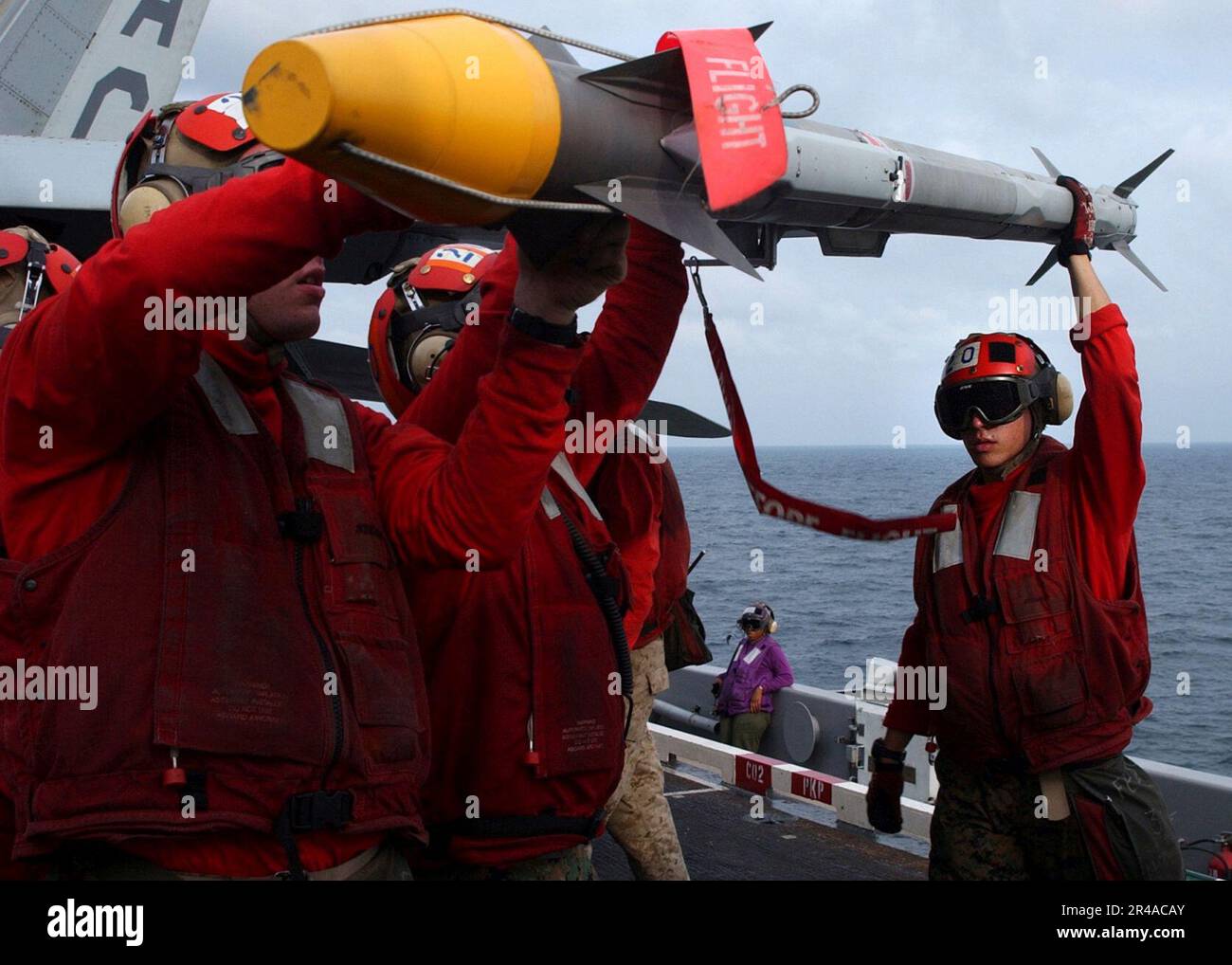 US Navy U.S. Marine ordnancemen load a AIM-9X Sidewinder missile on a wing pylon aboard an F-A-18A- Hornet Stock Photo