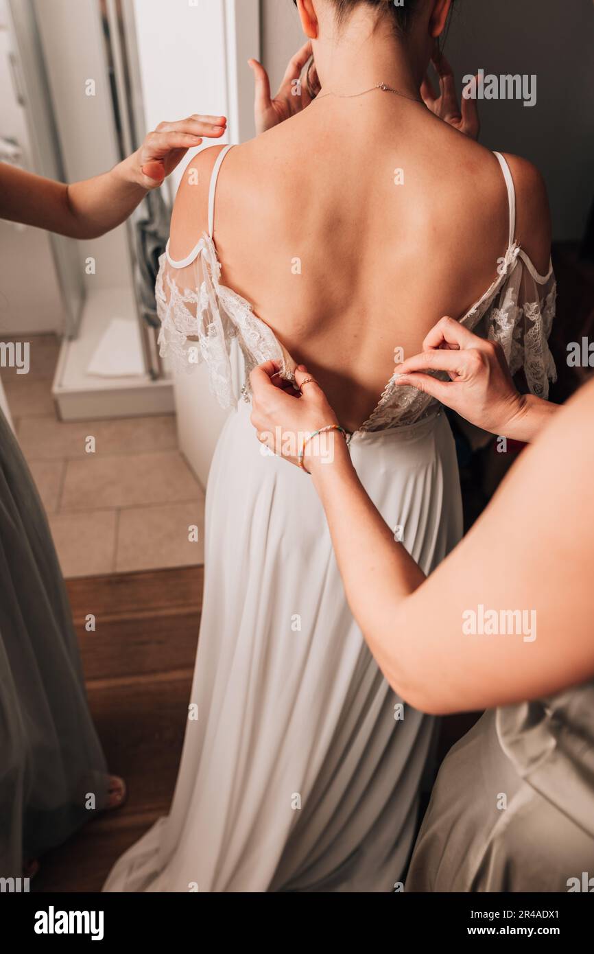 The bridesmaids helping the bride to put on her wedding dress Stock Photo