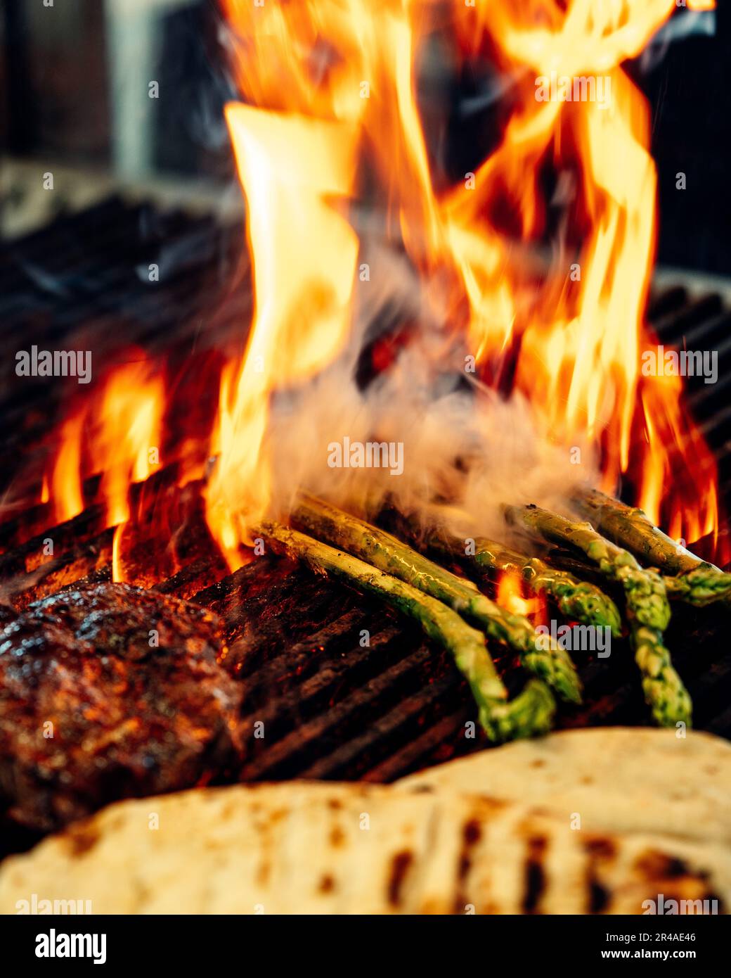 A close-up of a charcoal grill with a variety of meats, vegetables, and other food items being cooked Stock Photo