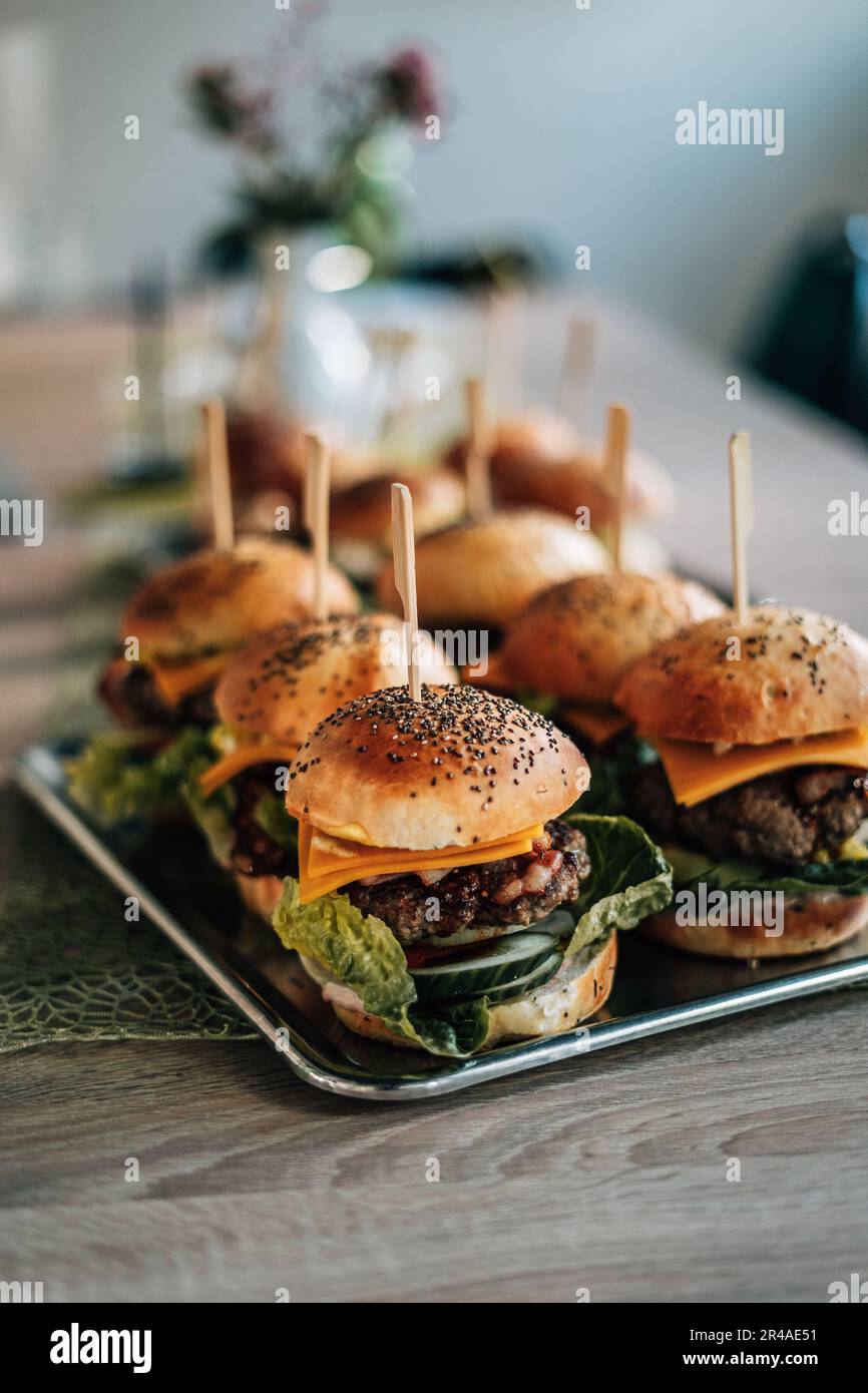 A platter filled with a variety of freshly-made hamburgers, garnished with toothpicks and served with condiments Stock Photo