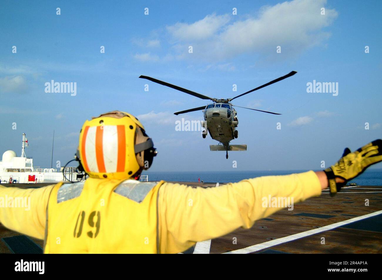 US Navy A Landing Signal Enlisted (LSE) guides a MH-60S Seahawk helicopter, assigned to Helicopter Combat Support Squadron Five (HC-5), for a landing aboard the Military Sealift Command (MSC) hospital ship U Stock Photo
