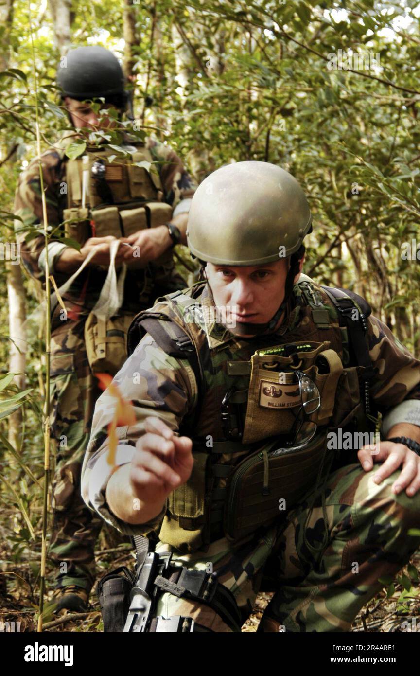 US Navy  Aviation Ordnanceman 2nd Class assigned to Explosive Ordnance Disposal Mobile Unit Five (EODMU-5), uses available shrubbery to check for trip wires during jungle warfare training exerci. Stock Photo