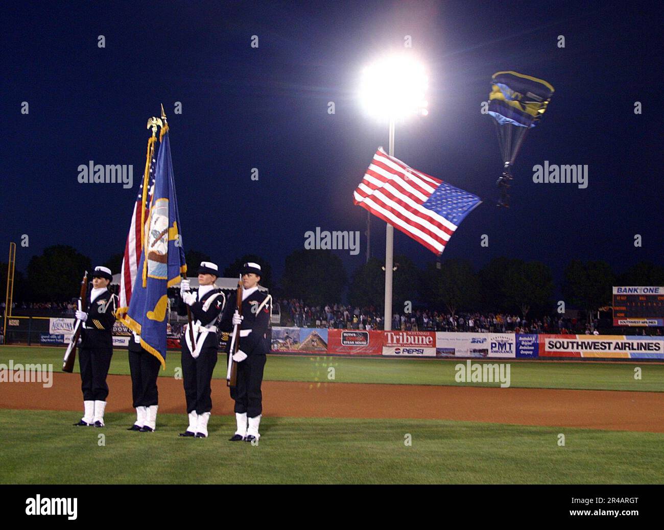 US Navy  A color guard from the Navy and Marine Corps Reserve Center, Phoenix, Ariz., post the colors as a U.S. Navy Leap Frogs parachute team member enters the stadium during a Cactus League spring training b. Stock Photo